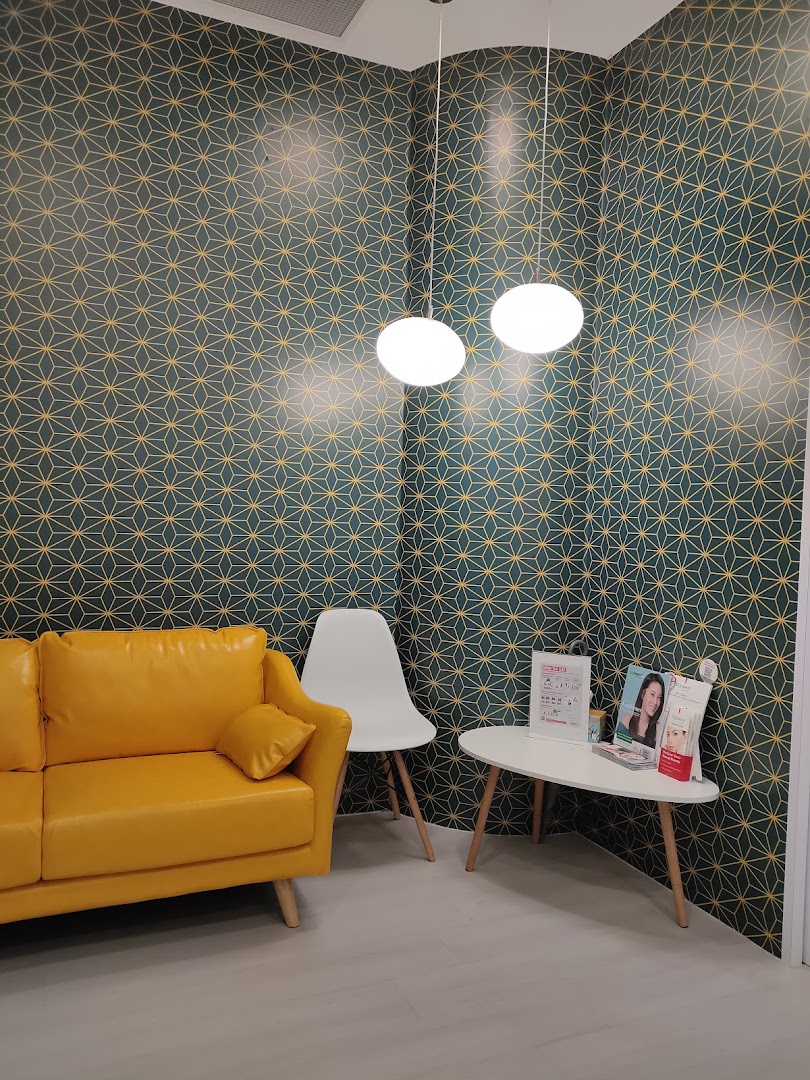 A vibrant waiting area with a yellow sofa, patterned wallpaper, and a small table with brochures.