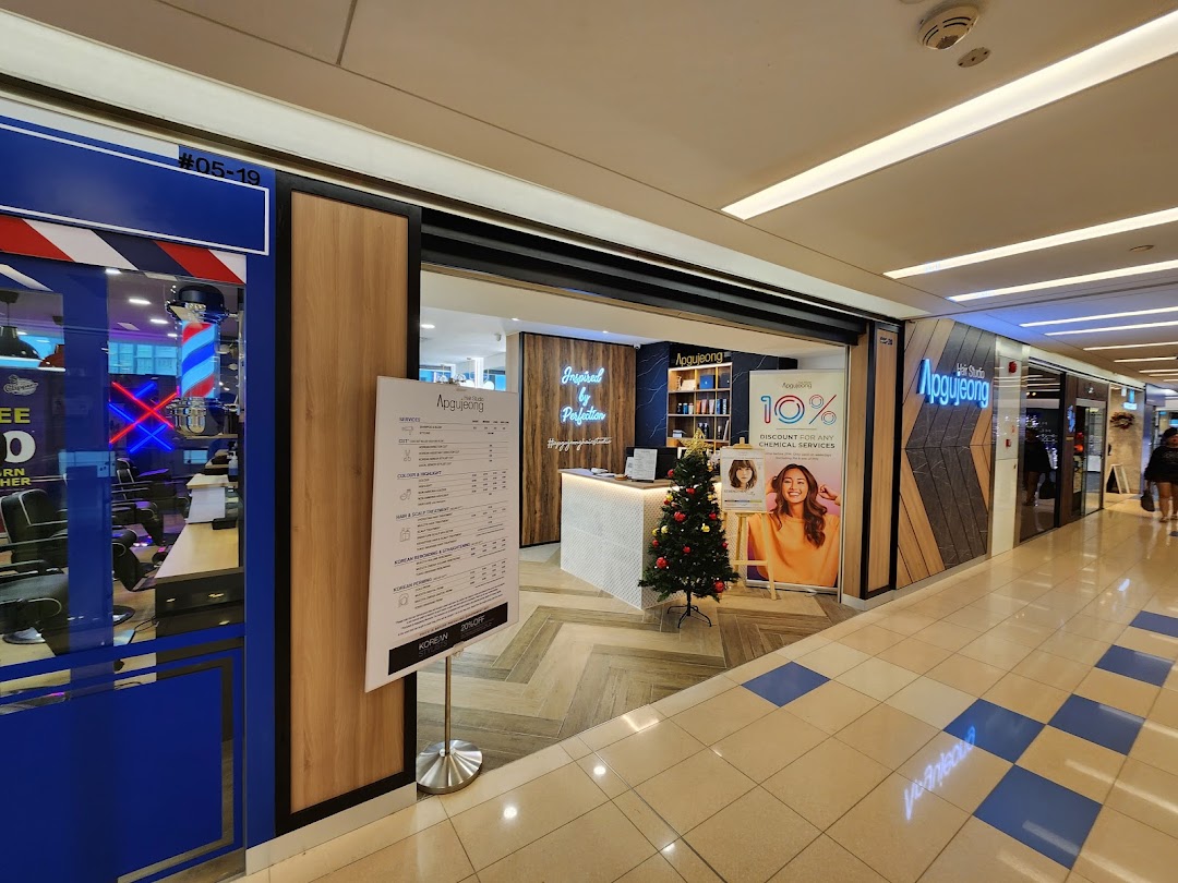 The shopfront of Apgujeong Hair Studio featuring a detailed services and price list, with festive decorations.
