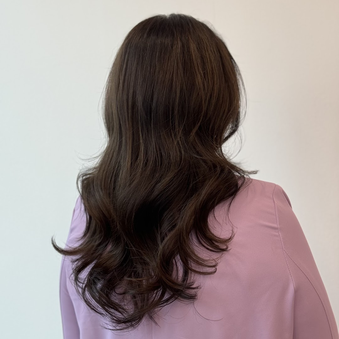 A close-up of a person's back, showcasing beautifully styled long, dark, wavy hair.