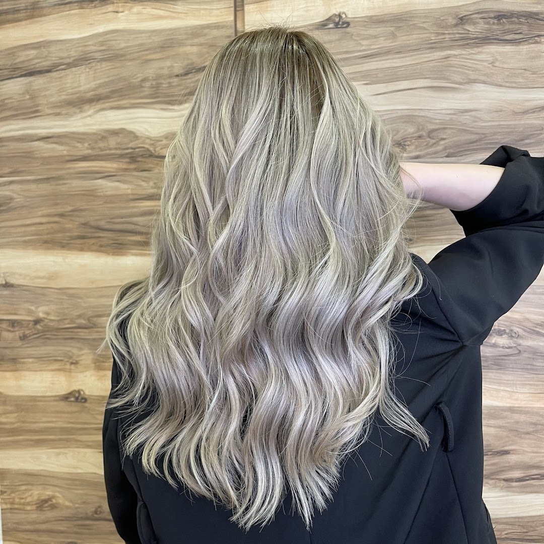 A person from behind showcasing long, wavy, ash blonde hair with highlights.