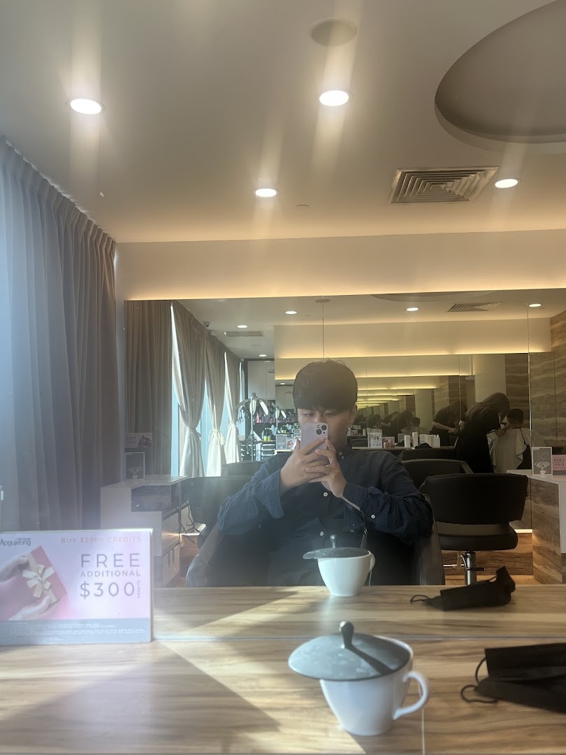 A customer sits in a modern hair studio, reflected in a mirror, with a promotional offer visible.