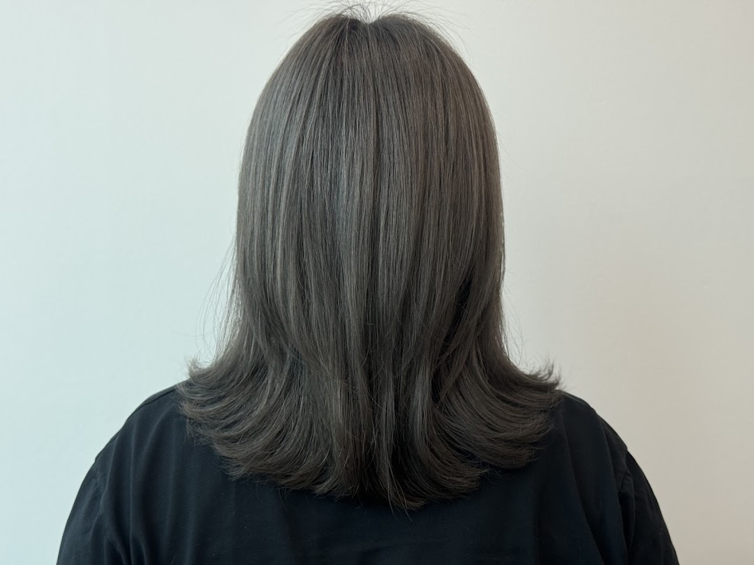 Rear view of a person showcasing a fresh, layered haircut with a stylish grey hair color.
