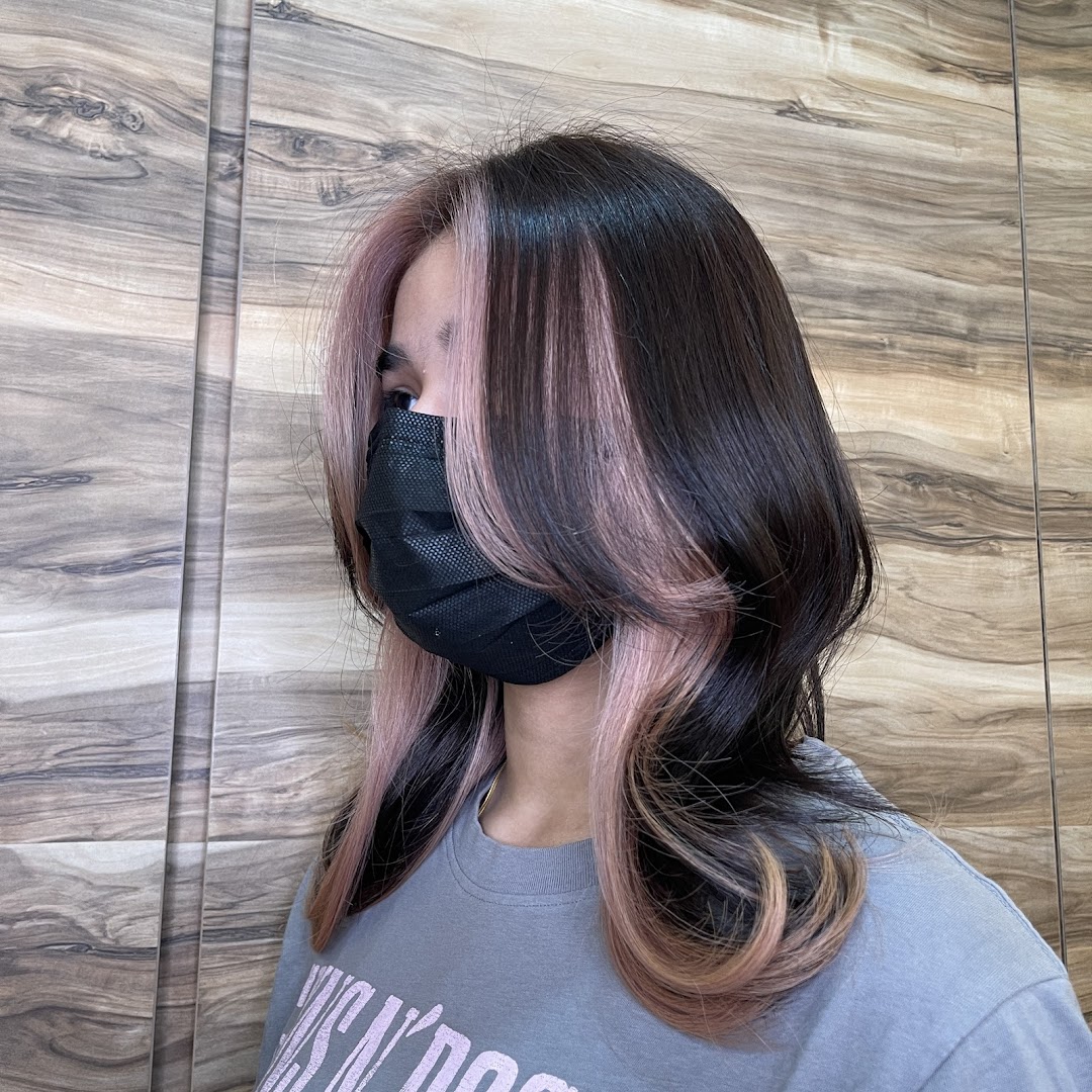 A person showcases a stylish new hair color with pink highlights and dark brown base.