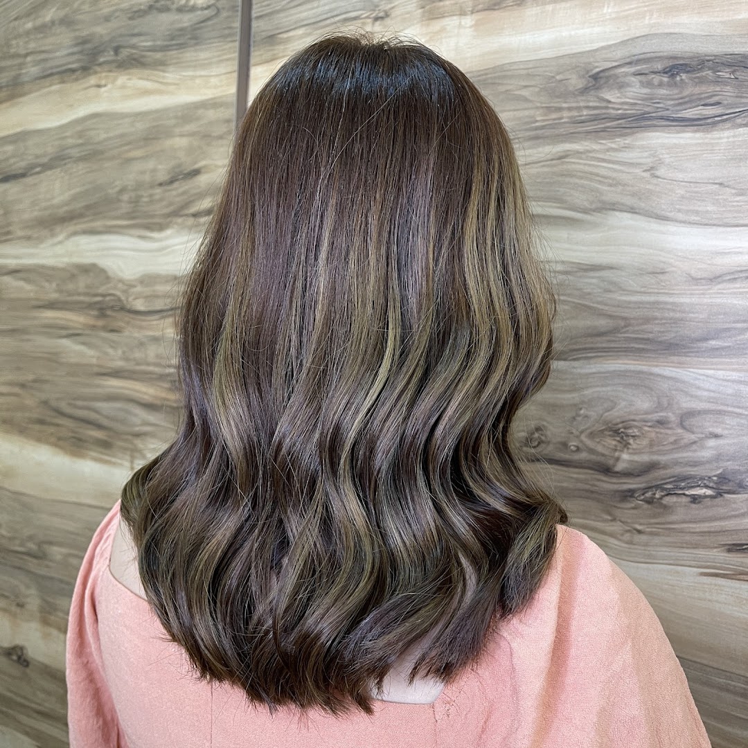 A client's back view showcasing beautifully styled hair with highlights and soft waves.