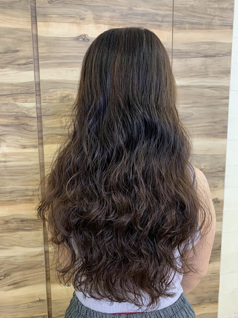 A person's long, dark brown, wavy hair viewed from the back, showcasing a hair treatment result.