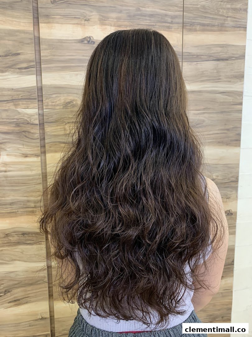 A person's long, dark brown, wavy hair viewed from the back, showcasing a hair treatment result.