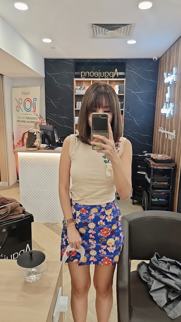 A person taking a mirror selfie inside Apgujeong Hair Studio, showcasing the salon's modern interior.