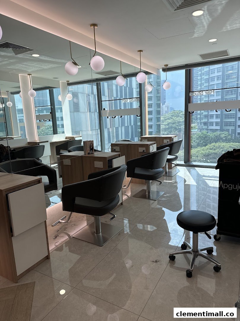 A bright, modern hair studio interior with multiple styling stations and large windows overlooking city buildings.