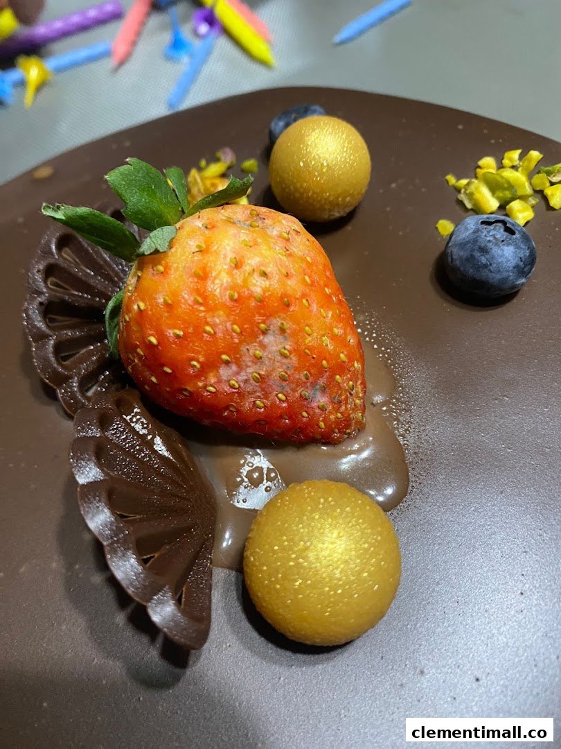 Close-up of a chocolate cake decorated with a fresh strawberry, blueberries, and golden spheres.