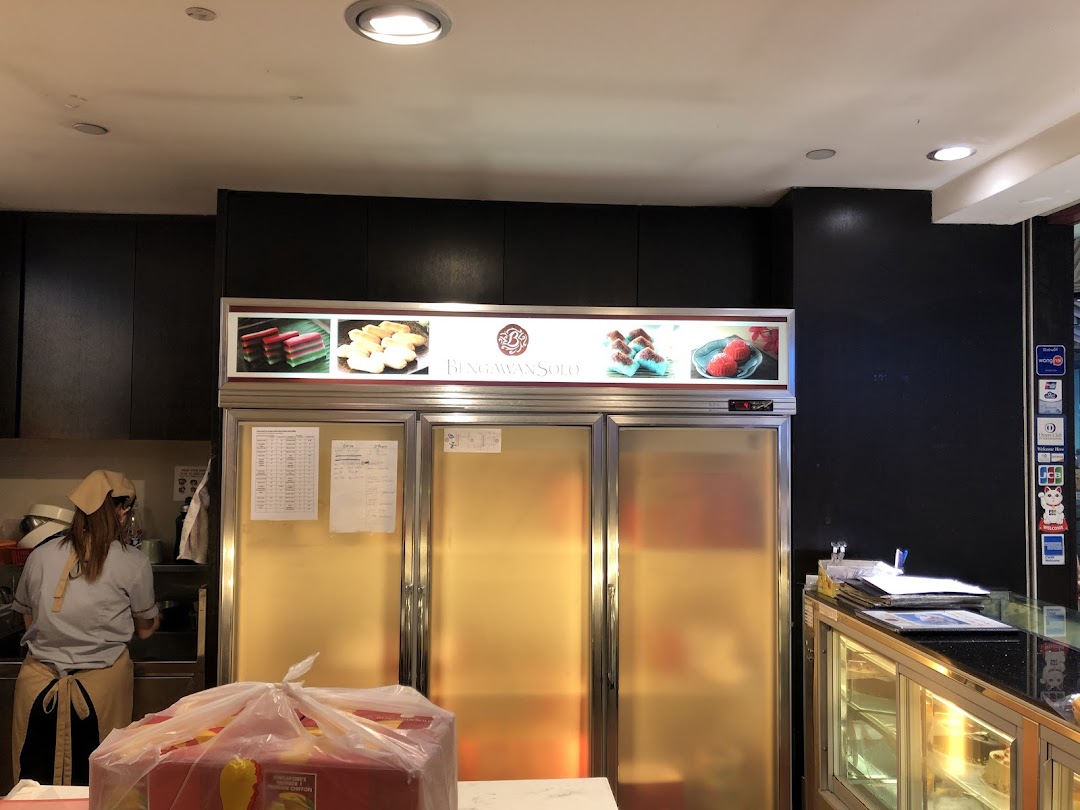 Interior view of Bengawan Solo, showcasing refrigerators, a staff member, and a product display.