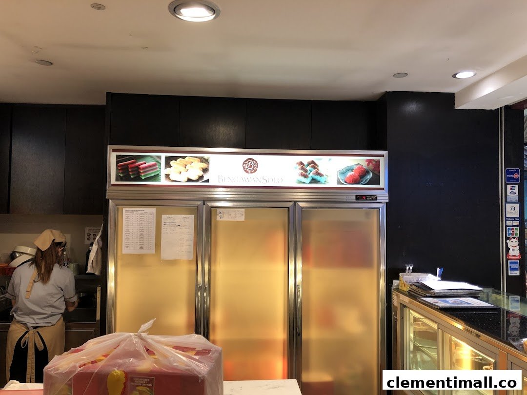 Interior view of Bengawan Solo, showcasing refrigerators, a staff member, and a product display.