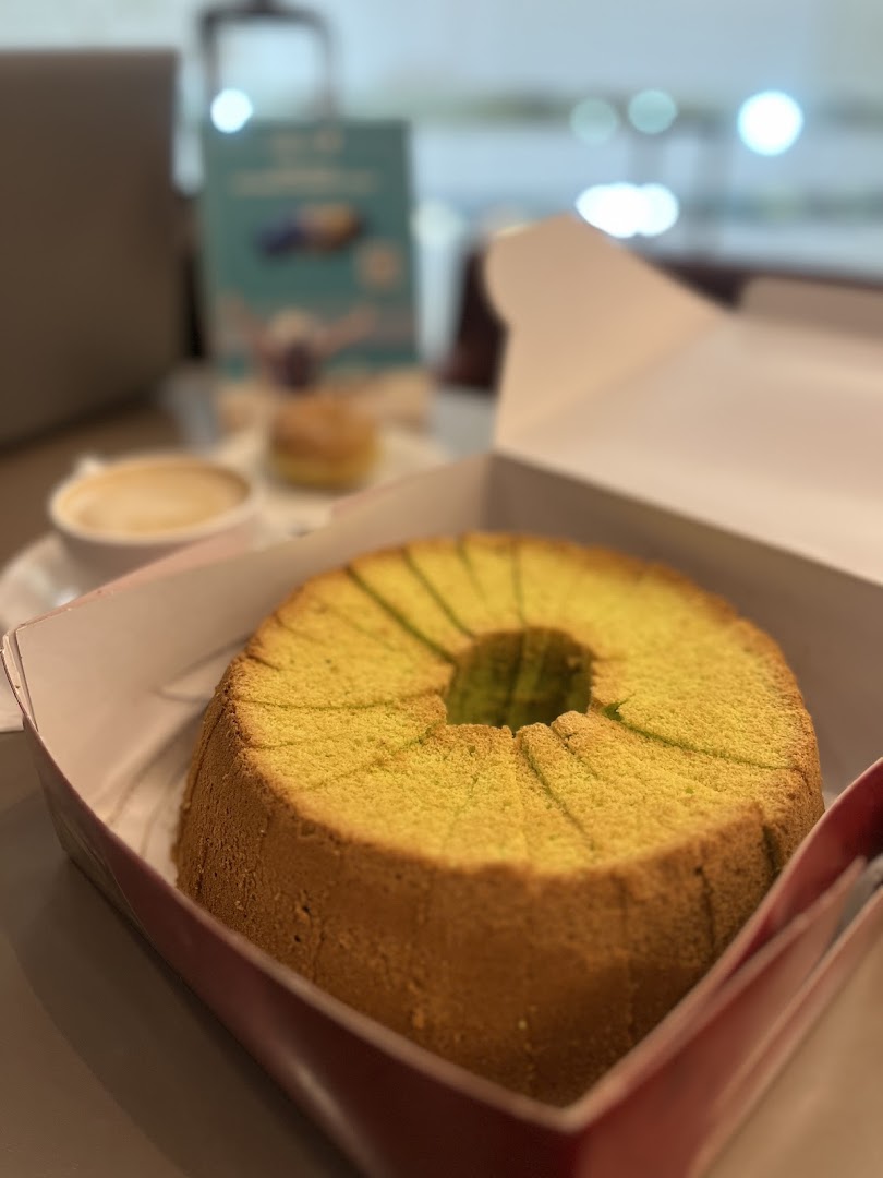 A delicious pandan chiffon cake in a box, accompanied by a cup of coffee.