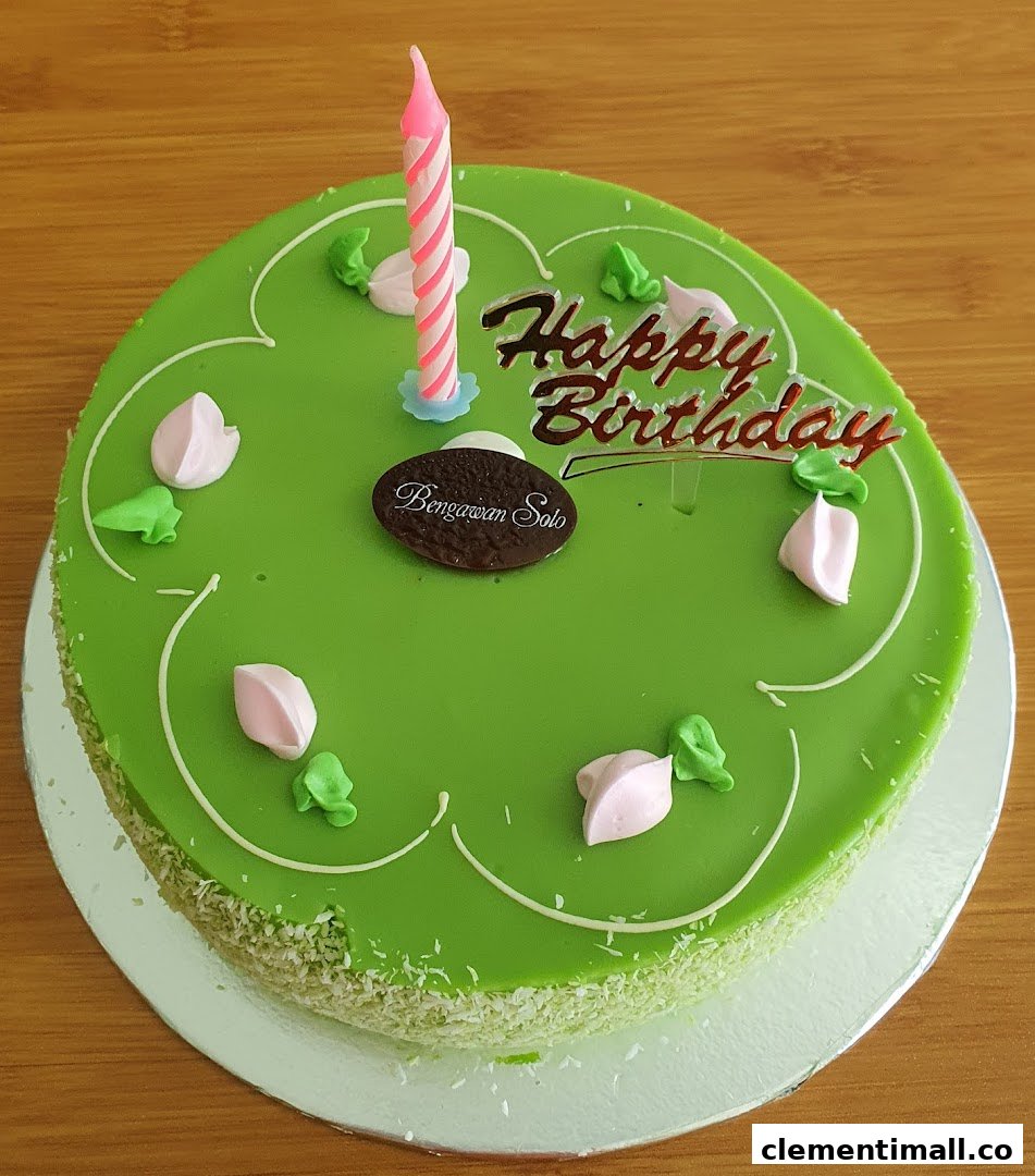 A vibrant green birthday cake from Bengawan Solo with a candle and 'Happy Birthday' topper.