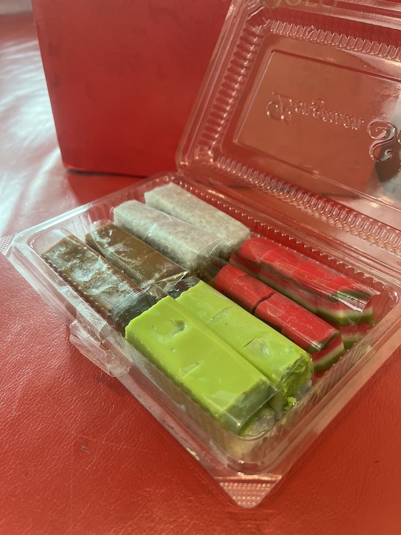 A clear plastic container holds an assortment of colorful traditional Indonesian sweets from Bengawan Solo.