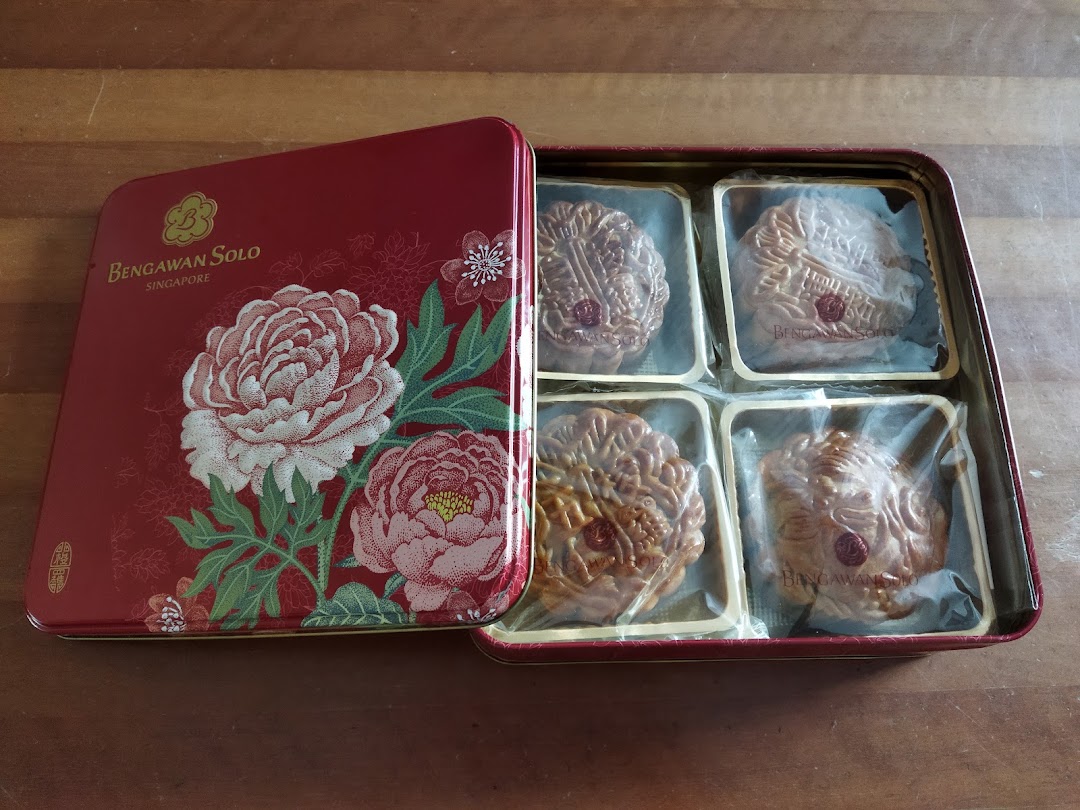A decorative red tin box from Bengawan Solo containing four individually wrapped mooncakes.