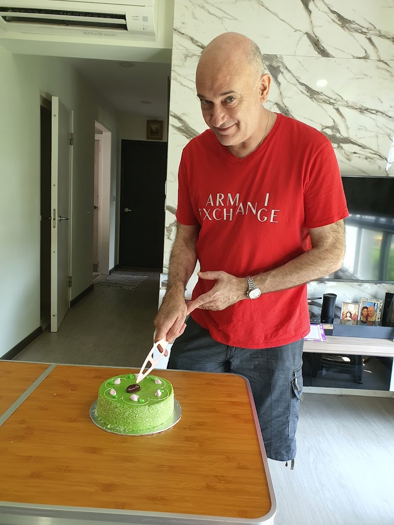 A man cutting a vibrant green cake from Bengawan Solo, showcasing the product.