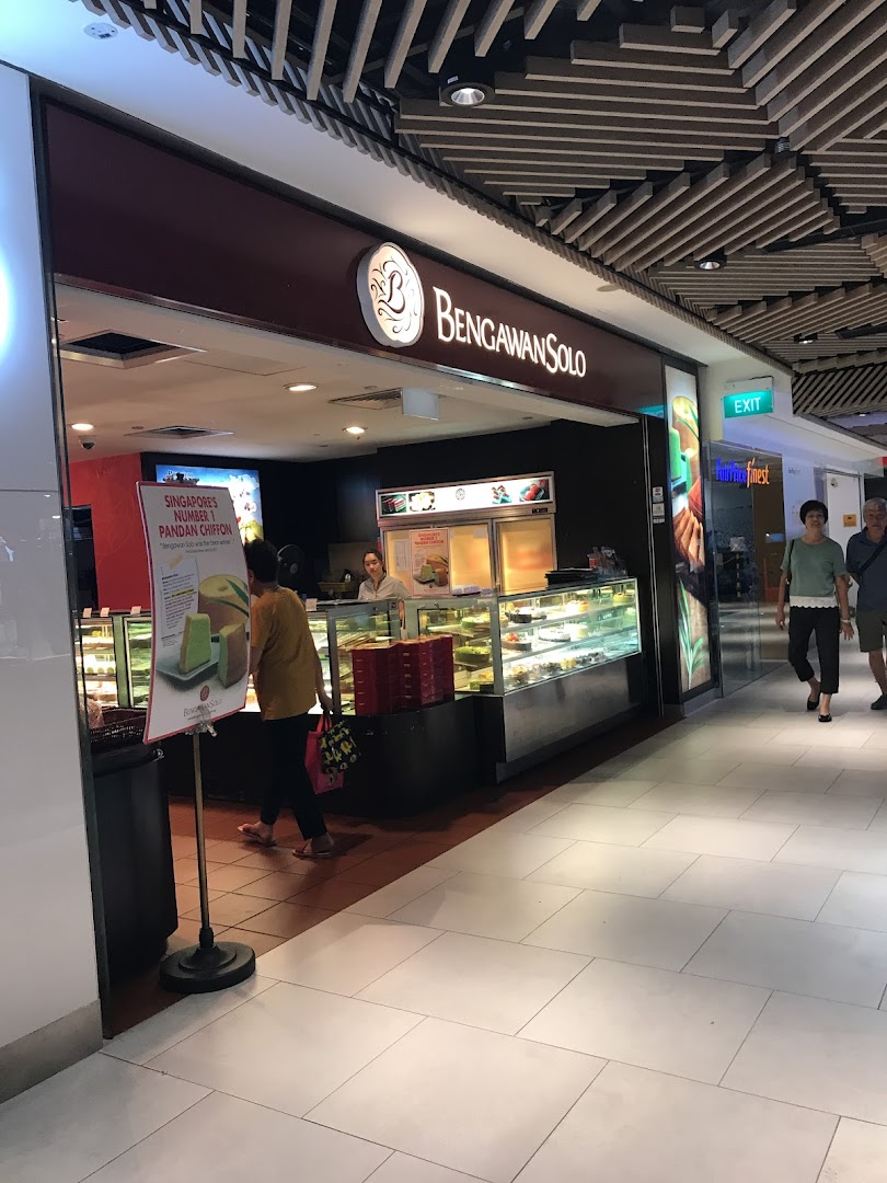 The shopfront of Bengawan Solo, featuring display cases filled with cakes and pastries, with customers nearby.