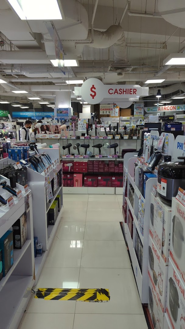 Interior view of Best Denki electronics store aisle, featuring various appliances and a cashier sign.