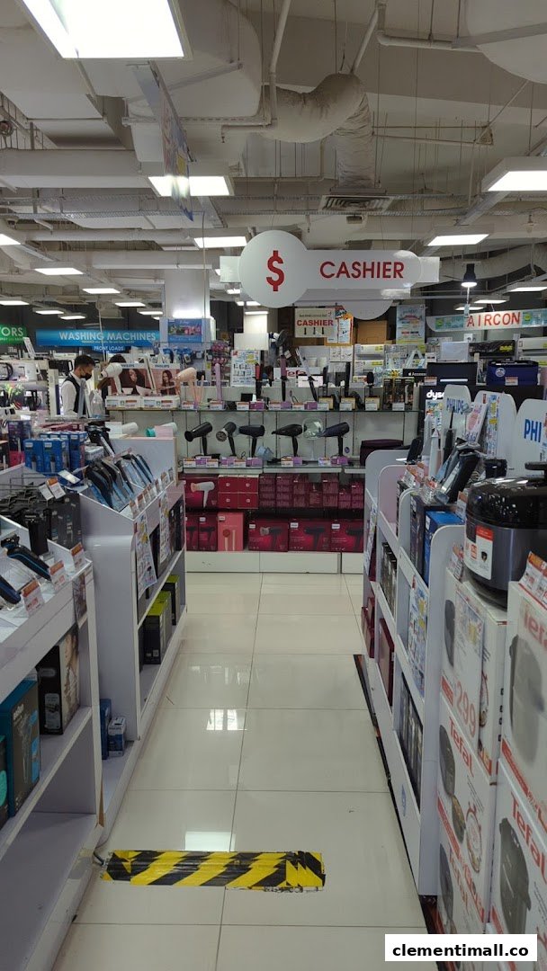 Interior view of Best Denki electronics store aisle, featuring various appliances and a cashier sign.
