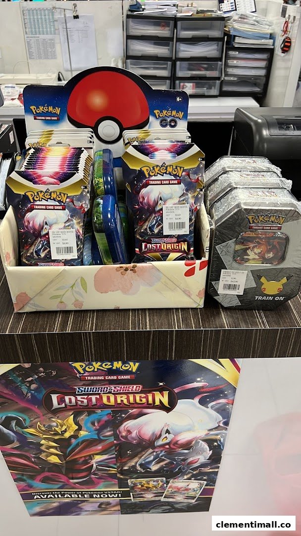 A display of Pokémon Trading Card Game products, including booster packs and tins, on a counter.