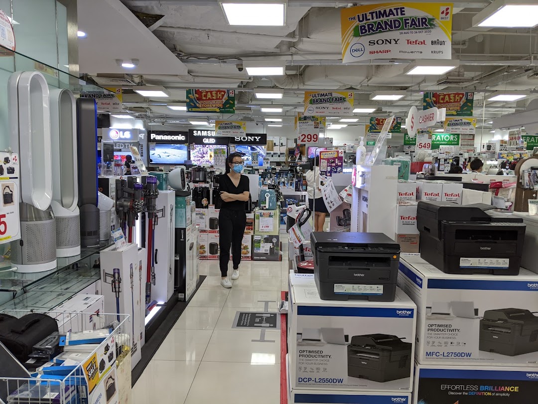 Interior view of Best Denki, an electronics store, showcasing various home appliances and a customer browsing.