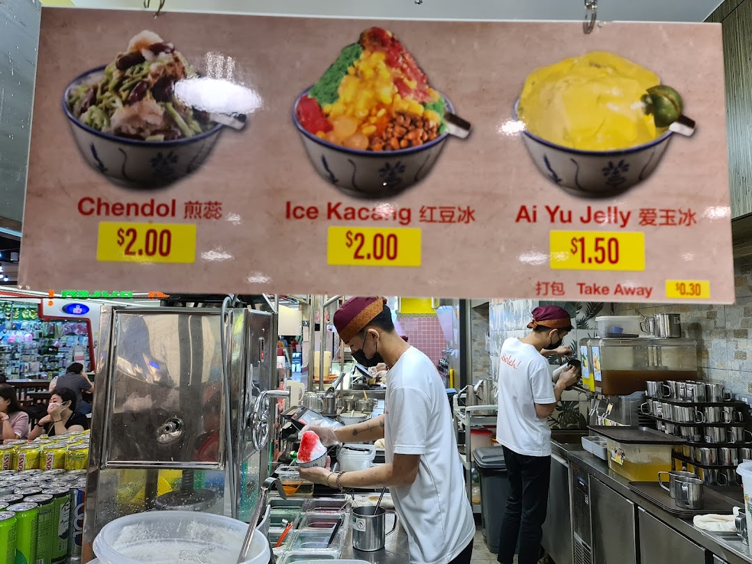A menu board displaying Chendol, Ice Kacang, and Ai Yu Jelly prices, with staff preparing desserts.