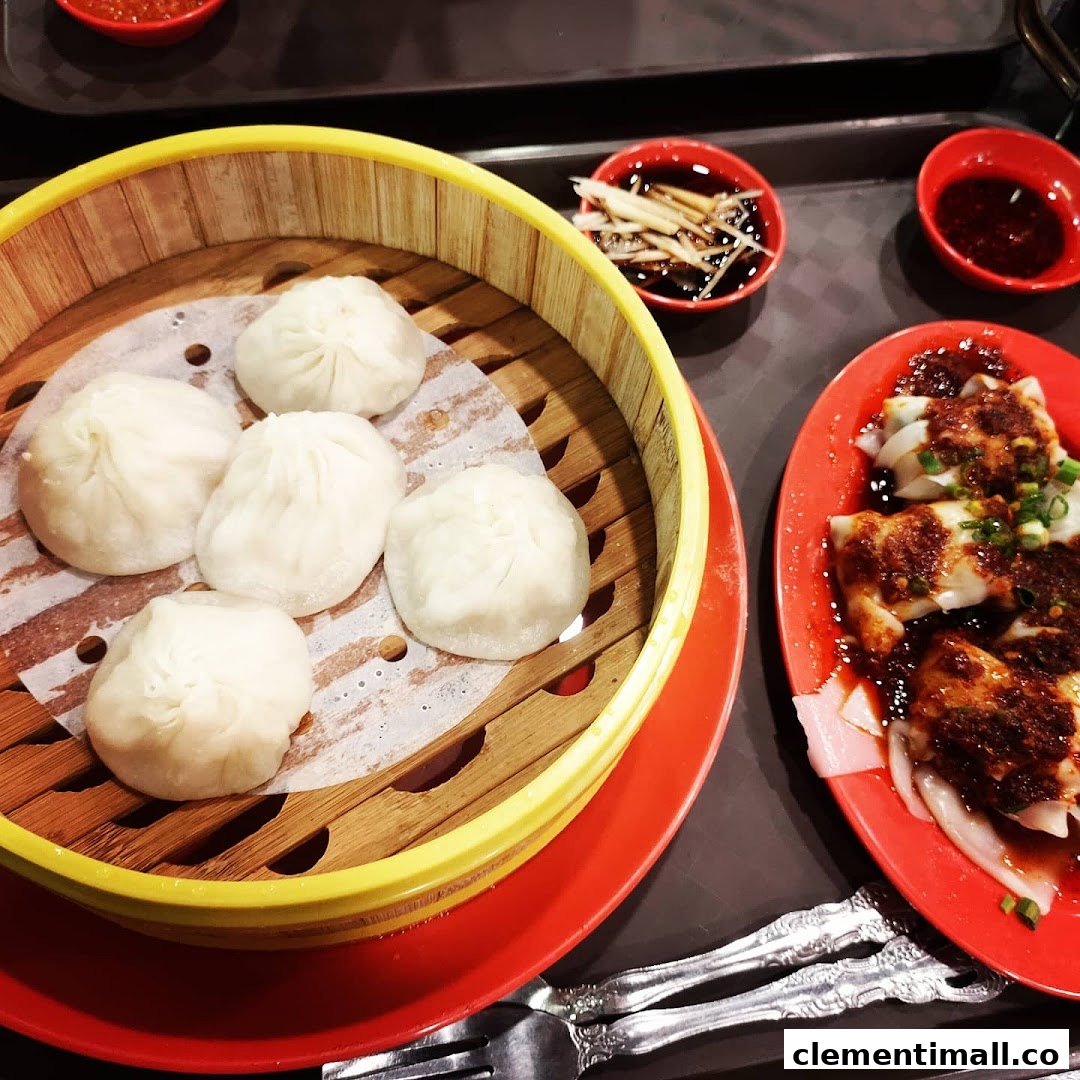 A close-up of delicious steamed dumplings in a bamboo basket and chili wontons on a red plate.