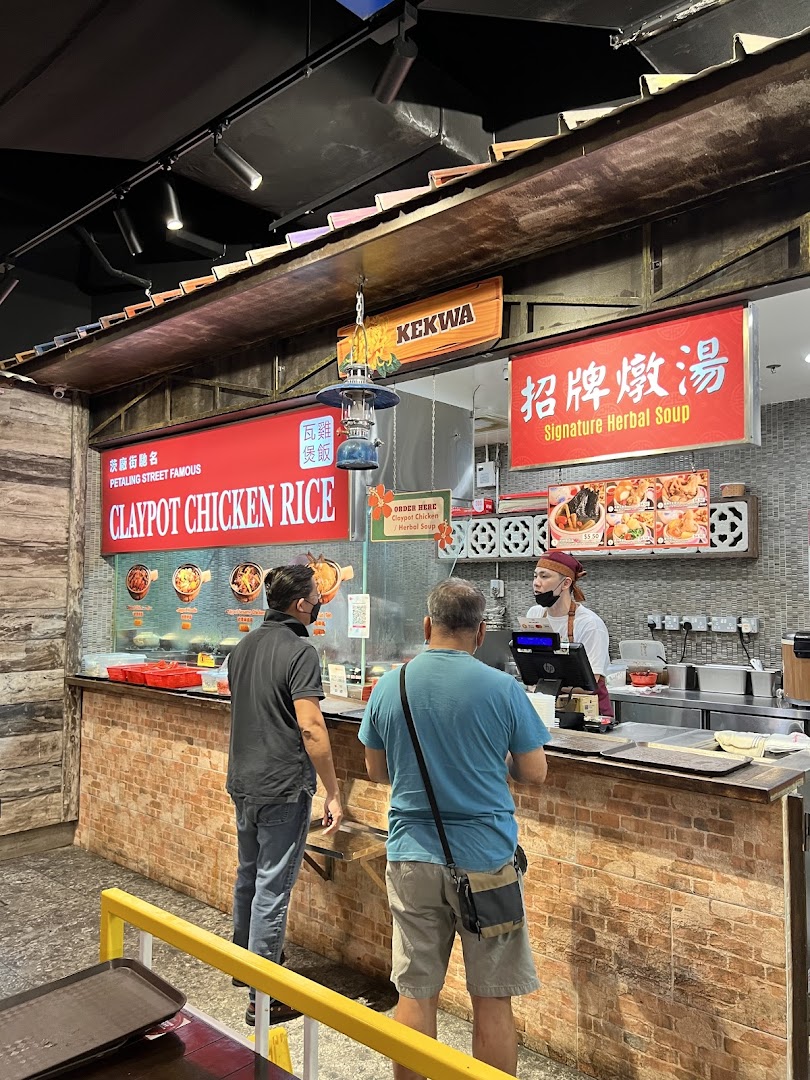 Customers ordering Claypot Chicken Rice and Signature Herbal Soup at a food stall counter.