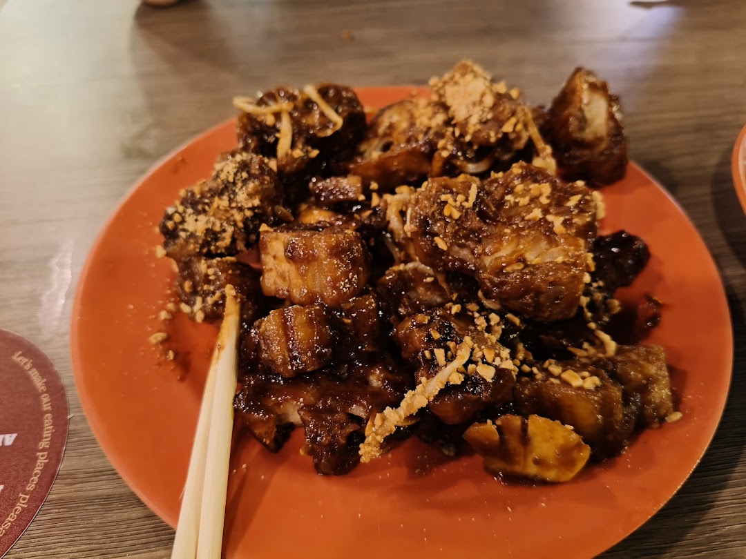 A close-up of a delicious plate of Rojak with dark sauce and crushed peanuts, served with chopsticks.