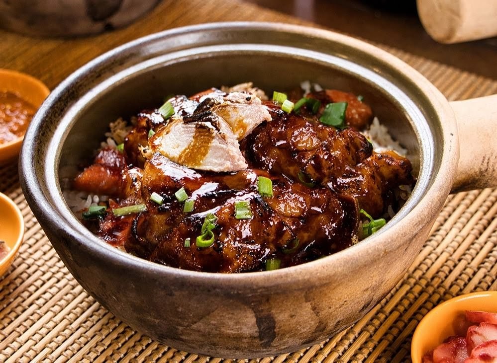 A close-up of a delicious claypot chicken rice dish, garnished with spring onions.