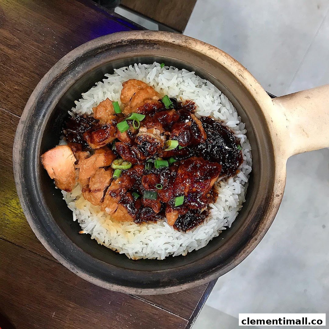 A close-up of a delicious claypot chicken rice dish, garnished with spring onions.