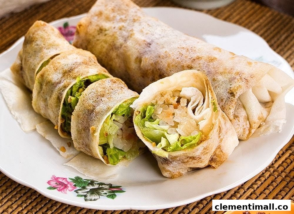 Two fresh spring rolls, one sliced to reveal crisp lettuce and savory filling, served on a white plate.