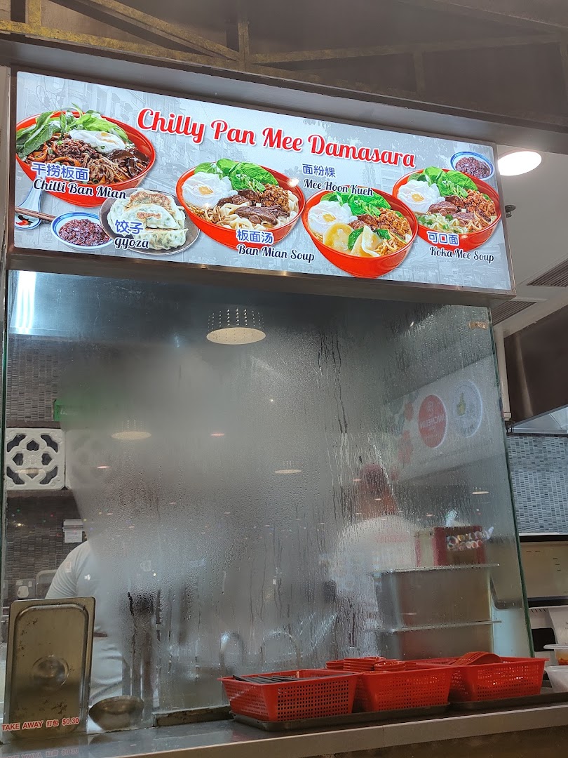 A vibrant menu board for 'Chilly Pan Mee Damasara' showcasing various noodle dishes and gyoza above a food stall counter.