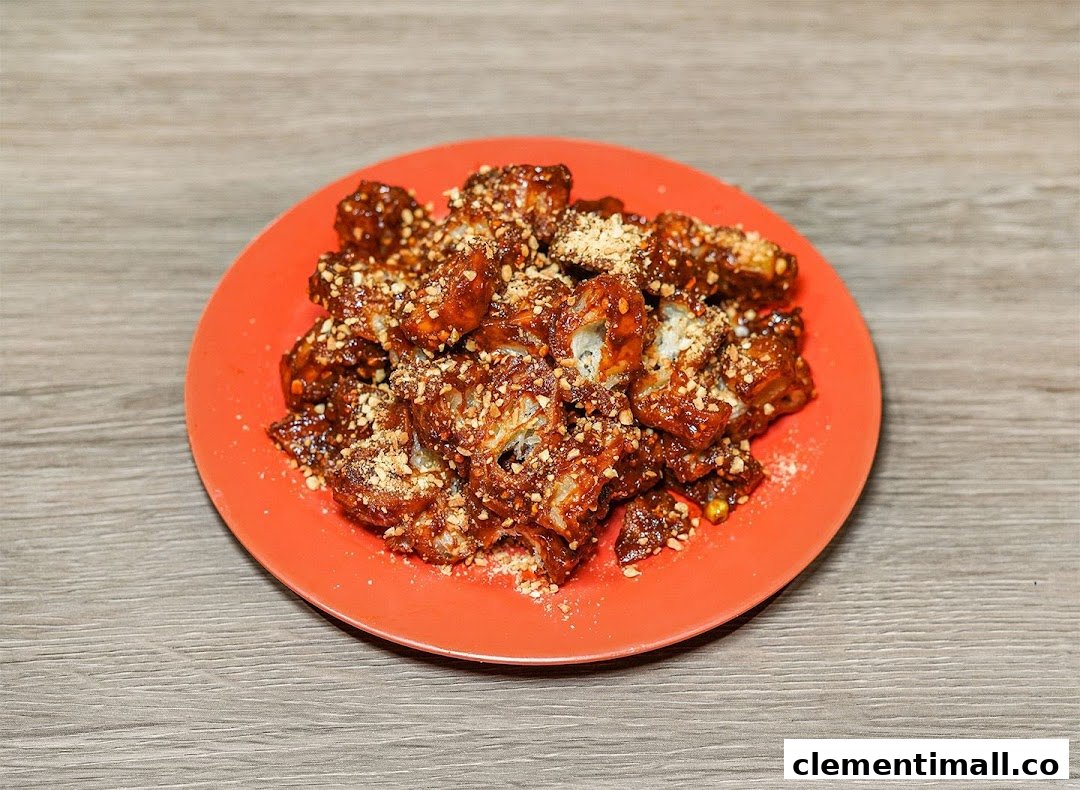A plate of deep-fried dough fritters coated in sweet sauce and crushed peanuts.