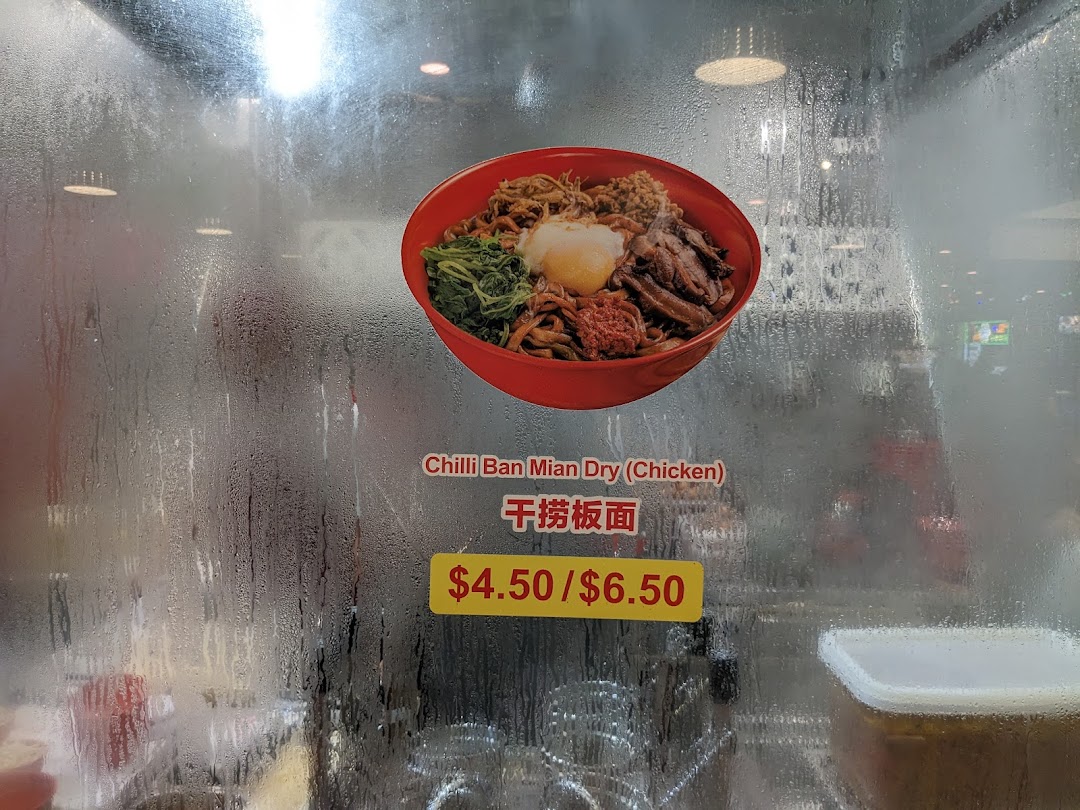A close-up of a steamed-up glass display featuring a delicious bowl of Chilli Ban Mian Dry (Chicken) with its price.