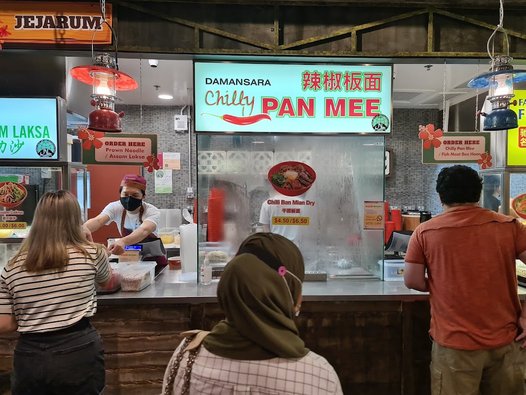 Customers ordering from Damansara Chilly Pan Mee and Jejrum Laksa stalls at a bustling food court.