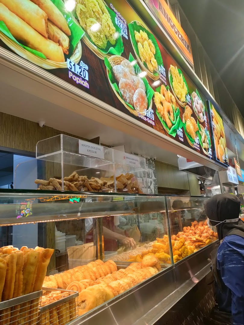 A vibrant display of fried local snacks at Boleh Boleh! with a clear menu board showing prices.
