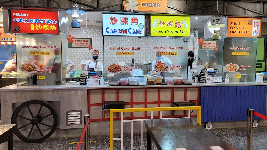 A bustling food stall counter showcasing various popular local dishes and their prices.