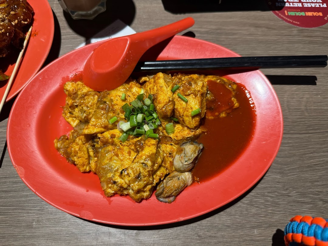 A vibrant red plate featuring a delicious oyster omelette garnished with spring onions, ready to be enjoyed.