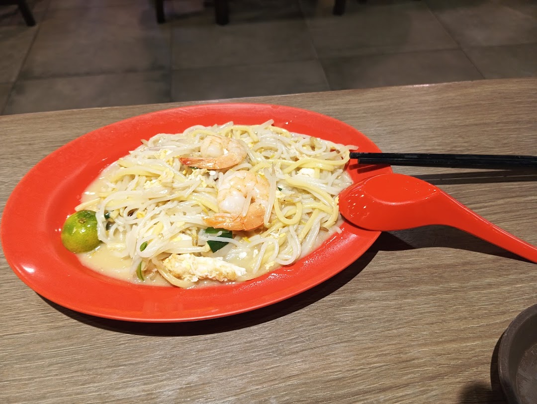 A vibrant plate of Hokkien Mee with fresh prawns and a calamansi lime.
