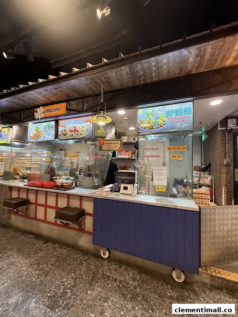 A vibrant food stall counter showcasing various local fried noodle and omelette dishes with prices.