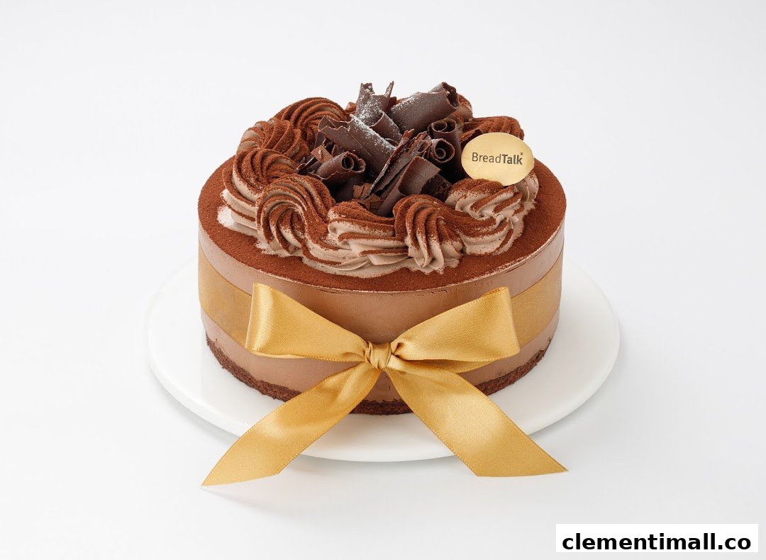 A decadent chocolate cake from BreadTalk, adorned with chocolate curls, cream, and a golden ribbon.