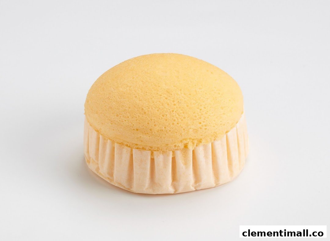A light, fluffy golden sponge cake in a paper liner on a clean white background.