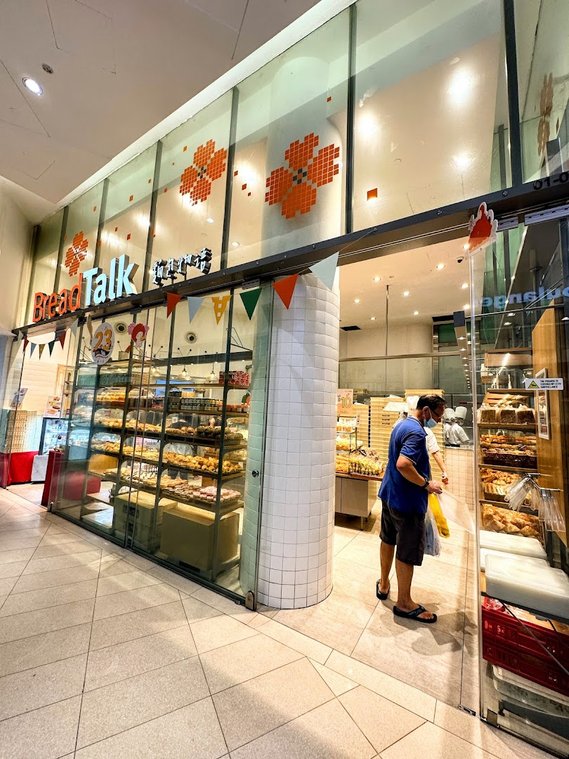 The inviting storefront of BreadTalk bakery, showcasing a variety of freshly baked goods and a customer entering.