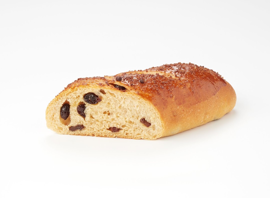 A golden-brown loaf of raisin bread, sliced to reveal its sweet, fruity interior.