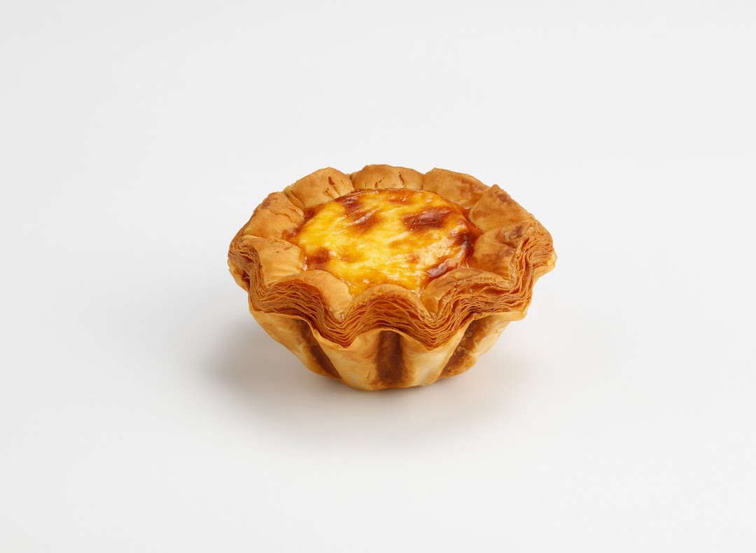 A single golden-brown egg tart with a flaky pastry crust on a clean white background.