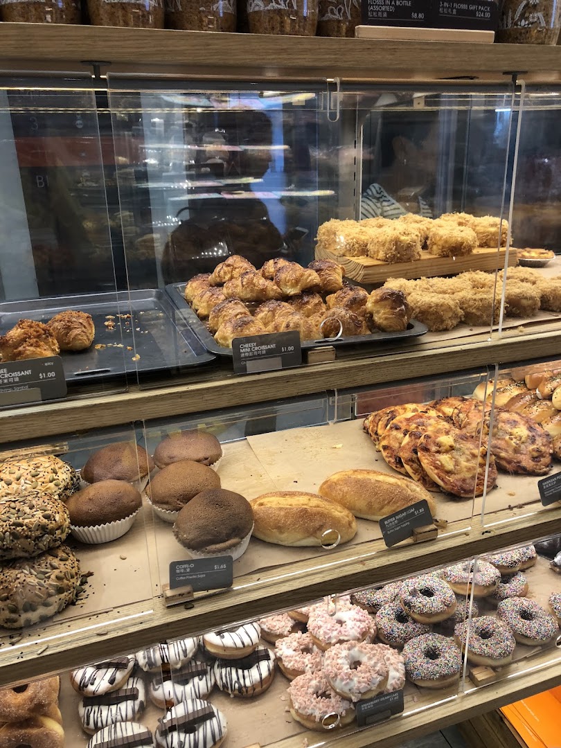 A vibrant display of freshly baked goods including croissants, donuts, and breads in a bakery showcase.