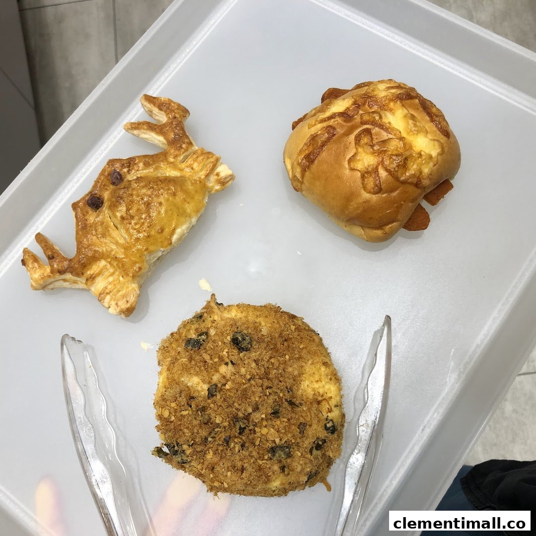 Three distinct baked goods, including a floss bun and a sausage bun, on a white tray with tongs.