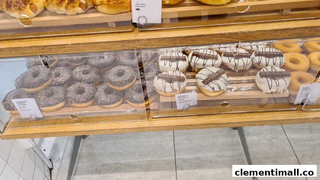 A display case filled with various freshly baked donuts, including chocolate sprinkle and Kit Kat varieties.
