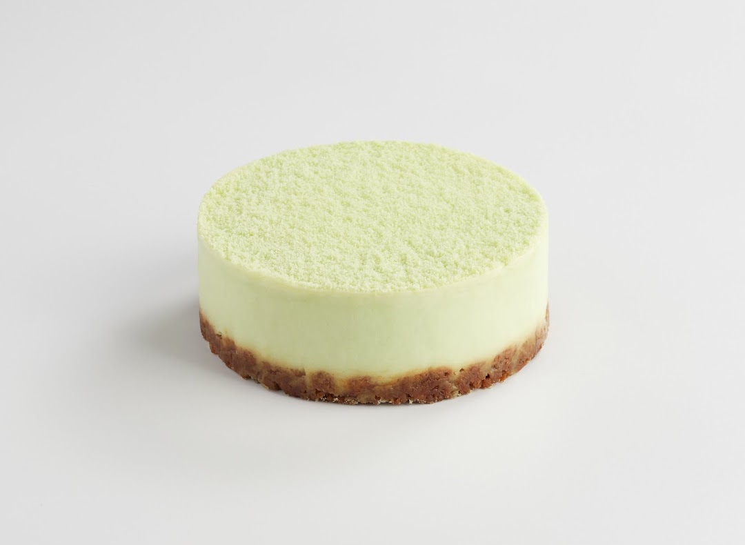 A light green cake with a crumbly top and a brown crust base on a white background.